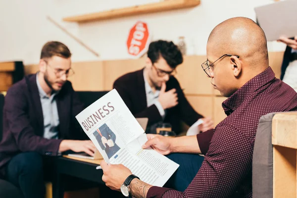 Afrikanisch Amerikanischer Geschäftsmann Liest Zeitung Mit Kollegen Der Nähe Café — kostenloses Stockfoto