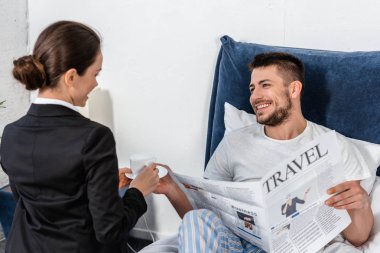 kahve için gülümseyen Erkek pijama yatak odasında sabah, sosyal rolü kavramı veren takım elbiseli kız