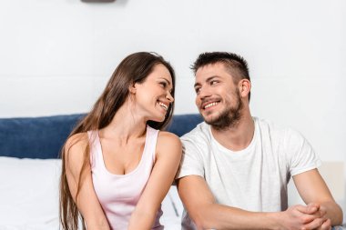 kız ve erkek yatakta yatak odasında oturma ve birbirine bakarak pijama gülümseyen