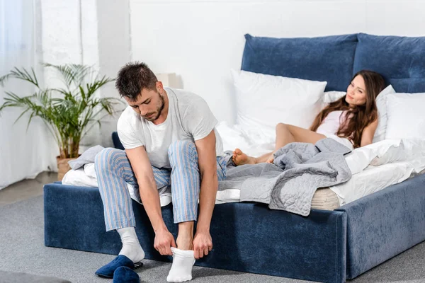 仰向けにベッドとベッドルームのソックスを履いてのパジャマを着て彼氏のガール フレンド  — 無料ストックフォト