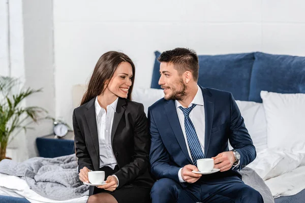 Sorrindo Namorada Namorado Ternos Sentados Cama Segurando Xícaras Café Manhã — Fotografia de Stock