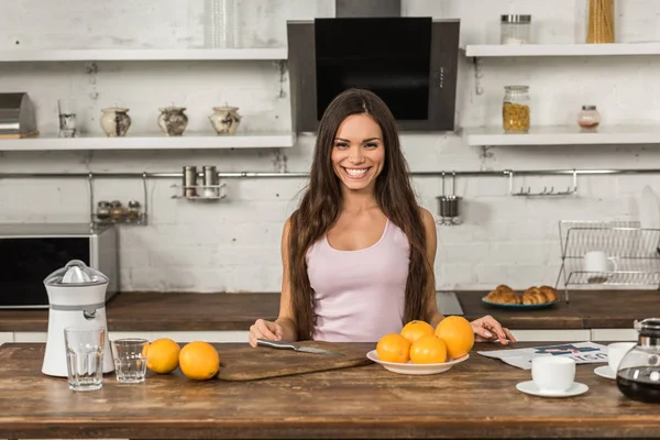 Beautiful Smiling Woman Standing Table Oranges Looking Camera Morning Kitchen — Free Stock Photo