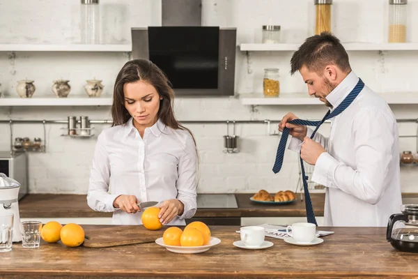Boyfriend Tying Tie Girlfriend Cutting Oranges Morning Kitchen — Free Stock Photo