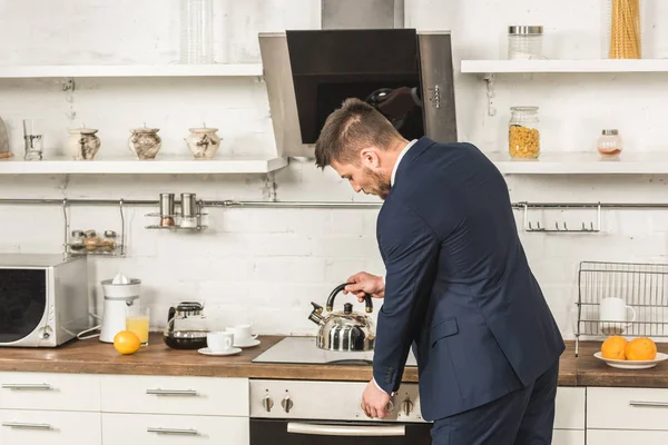 Handsome Man Suit Putting Kettle Stove Morning Kitchen — Stock Photo, Image