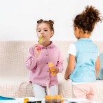 Hermosos niños multiétnicos jugando con burbujas de jabón juntos