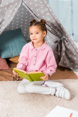 kitap ve kameraya gülümseyen güzel çocuk