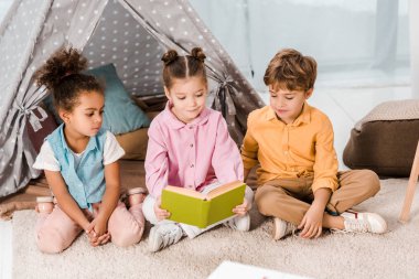 sevimli küçük çocuk halı üzerinde oturan ve birlikte kitap okuma 