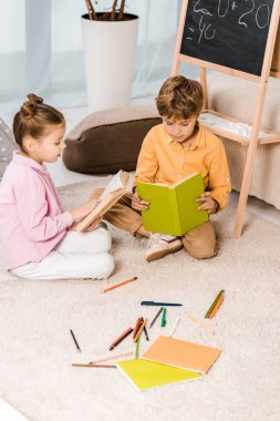 halı üzerinde oturan ve birlikte kitap okumak çok güzel odaklı çocuk yüksek açılı görünüş   