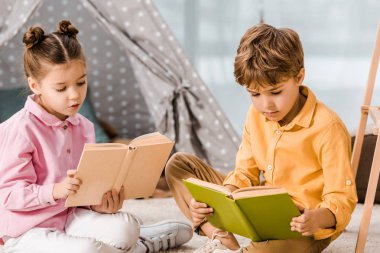 şirin odaklı çocuk halı üzerinde oturan ve birlikte kitap okuma   