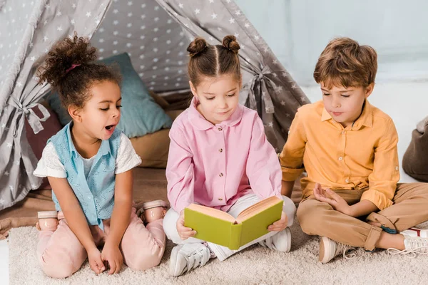 sevimli küçük çocuk halı üzerinde oturan ve birlikte kitap okuma 