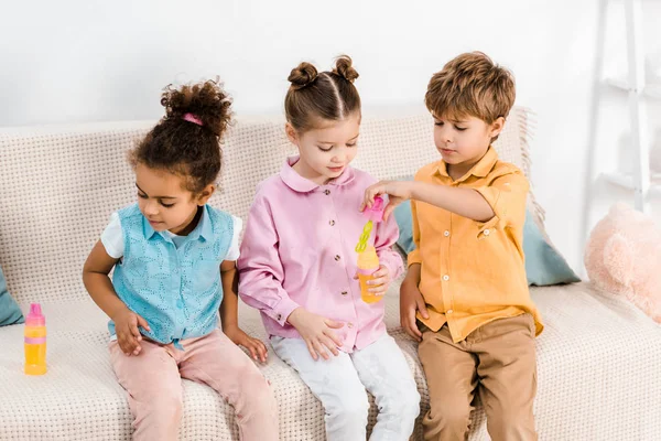 Cute Multiethnic Children Sitting Sofa Playing Soap Bubbles Together — Stock Photo, Image