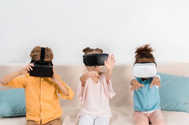 sevimli küçük koltukta oturan ve sanal gerçeklik kulaklık kullanarak çocuklar 