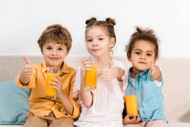 suyu gözlük tutan ve başparmak gösterilmesini şirin çok ırklı çocuklar 