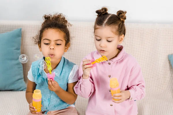 Beautiful Multiethnic Children Sitting Sofa Blowing Soap Bubbles — Free Stock Photo