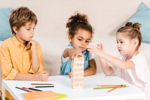 Adorables Niños Multiétnicos Construyendo Torre Bloques Madera Mesa —  Fotos de Stock