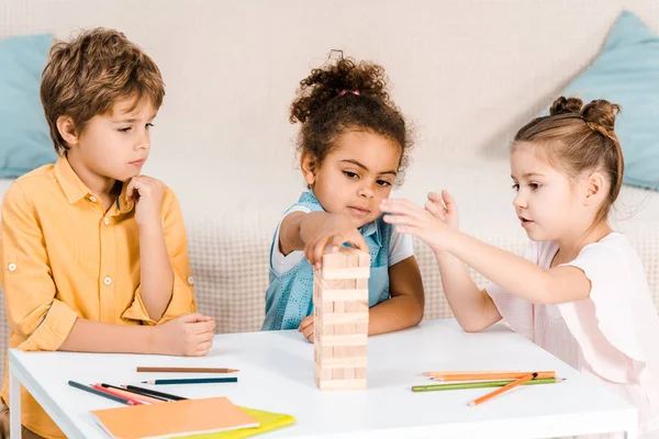 Adorables Niños Multiétnicos Construyendo Torre Bloques Madera Mesa — Foto de Stock