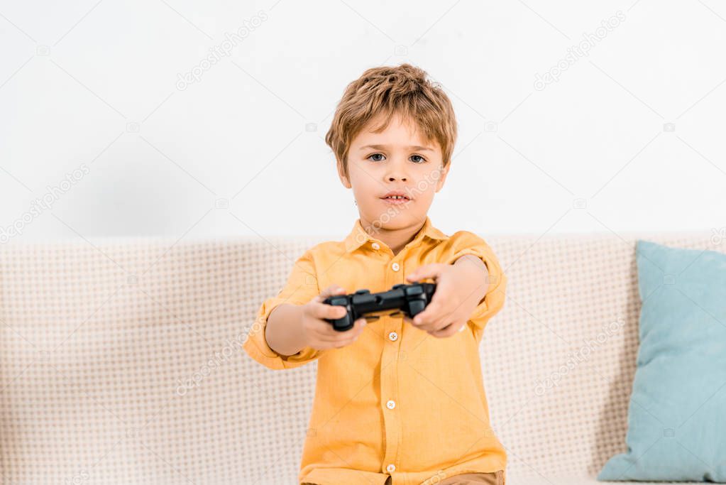 cute little boy playing with joystick and looking at camera