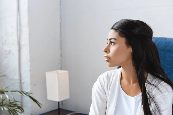 Schönes Mischlingsmädchen Weißem Gewand Sitzt Auf Dem Bett Und Schaut — Stockfoto