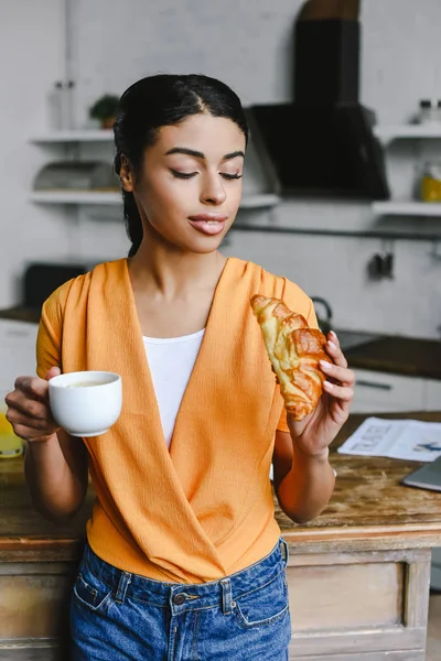 Beautiful Mixed Race Girl Orange Shirt Holding Cup Coffee Croissant — Free Stock Photo