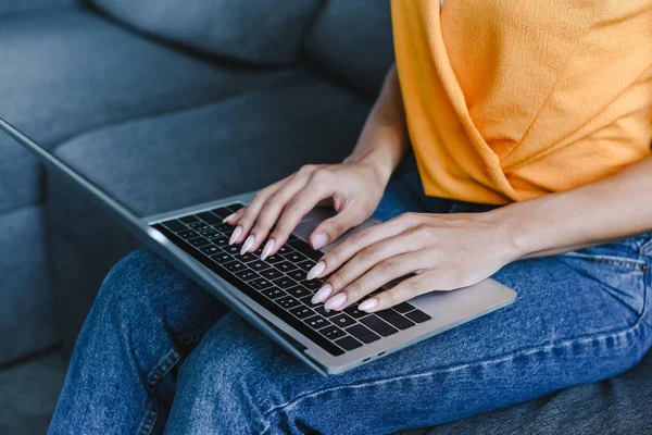 Abgeschnittenes Bild Eines Mischlingsmädchens Orangefarbenem Hemd Mit Laptop Auf Sofa — kostenloses Stockfoto