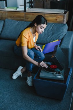 güzel karışık yarış kız retro vinil evde gramofon açma turuncu gömlekli yüksek açılı görünüş