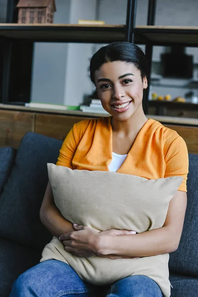 Smiling Beautiful Mixed Race Girl Orange Shirt Hugging Pillow Looking — Free Stock Photo