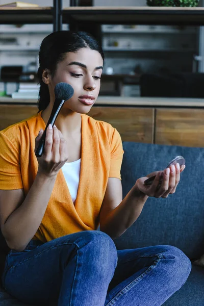 Atractiva Chica Raza Mixta Camisa Naranja Aplicando Polvo Facial Casa — Foto de stock gratis