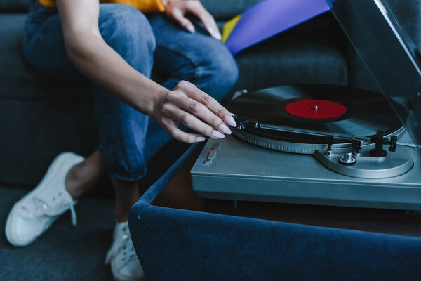 cropped image of mixed race girl turning on gramophone with retro vinyl at home