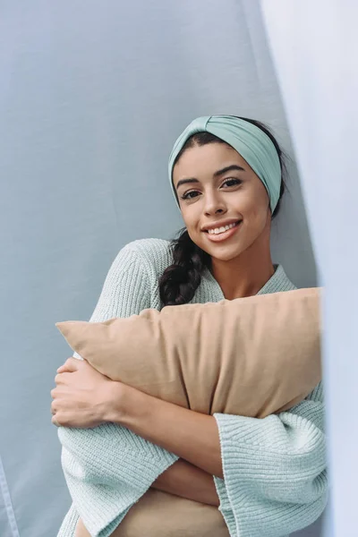 Smiling Beautiful Mixed Race Girl Turquoise Sweater Headband Hugging Pillow — Free Stock Photo