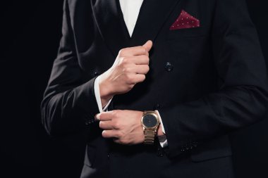 cropped view of man adjusting cufflinks on suit isolated on black clipart