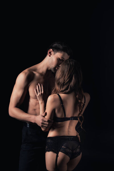 undressed couple hugging and kissing isolated on black