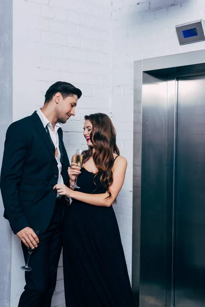 Happy Couple Holding Champagne Glasses Talking Waiting Elevator — Stock Photo, Image