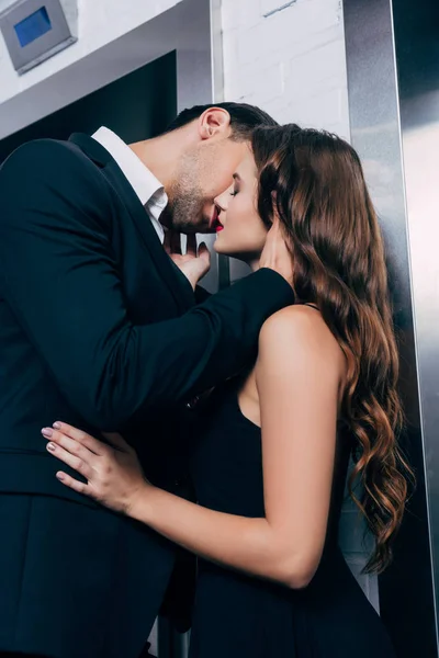 エレベーター近くの美しい女性を情熱的にキス スーツの男 — ストック写真