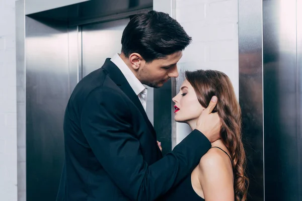 男子在西装触摸美丽的女人的脸 而等待电梯 — 图库照片
