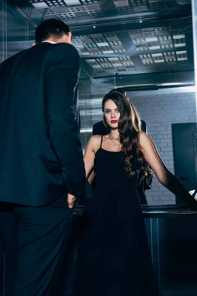 Beautiful Seductive Woman Black Dress Looking Camera Man Foreground Elevator — Stock Photo, Image