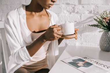 Kırpılan Kupası beyaz mutfak tutan Afrikalı-Amerikalı kadın görünümünü 