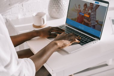 Afrikalı-Amerikalı kadın couchsurfing Web sitesi ile Laptop yazarak görünümünü kırpılmış