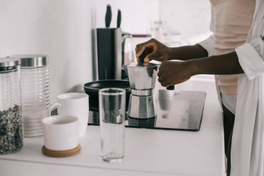 Afrikalı-Amerikalı kadın hazırlama kahve beyaz mutfak görünümünü kırpılmış 