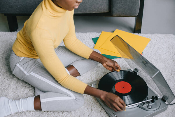 cropped view of african american woman using record player on carpet