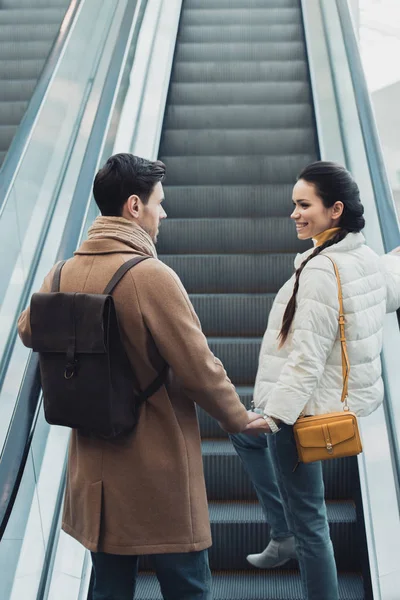 Smiling Couple Warm Clothing Holding Hands Going Escalator — Free Stock Photo