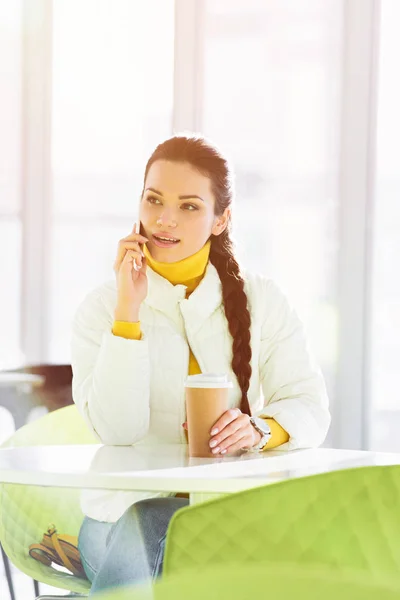 Smiling Girl Sitting Table Talking Smartphone Holding Disposable Cup Cafe — Free Stock Photo