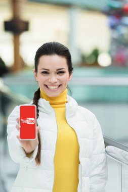 Kamera ve gösteren smartphone ekran youtube uygulaması ile bakarak kız gülümseyerek