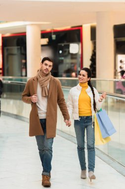 Kağıt bardak ve alışveriş merkezinde alışveriş torbaları ile çekici kız yakışıklı adam