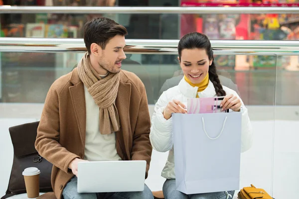 Handsome Man Laptop Smiling Girl Shopping Bag Sitting Bench Mall — Free Stock Photo