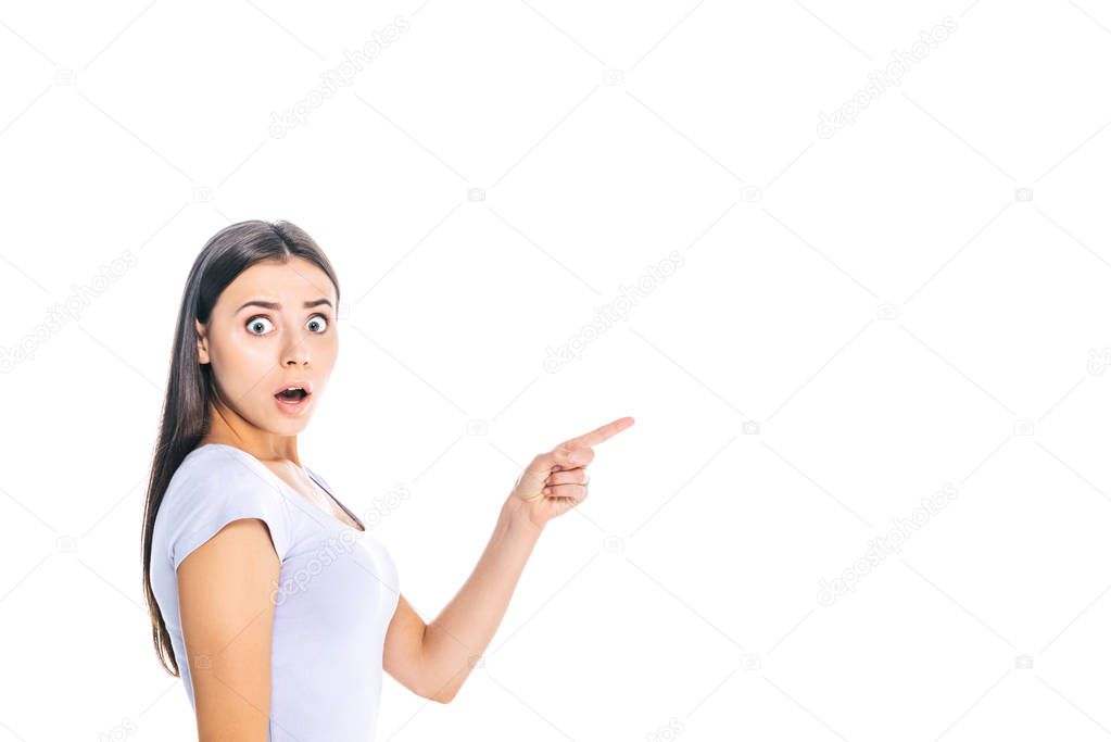 side view of shocked young woman pointing away isolated on white