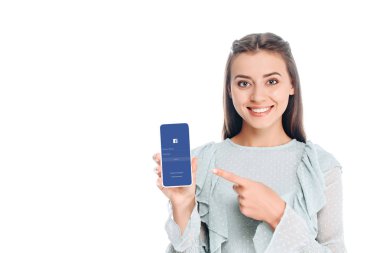 kadın gösteren smartphone ile facebook logo üstünde perde üzerinde beyaz izole gülümseyen