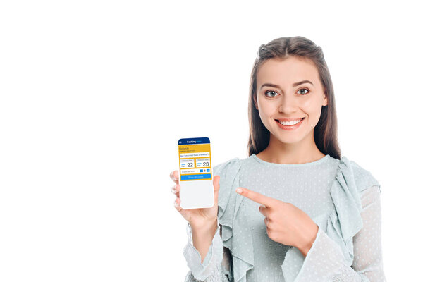 smiling woman showing smartphone with booking website on screen isolated on white