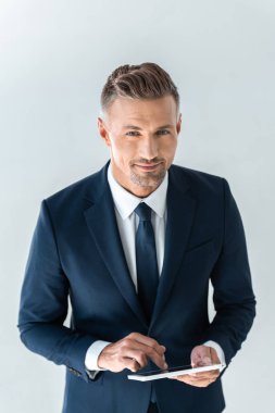 tablet kullanarak ve üzerinde beyaz izole kamera bakarak gülümseyen yakışıklı işadamı yüksek açılı görünüş