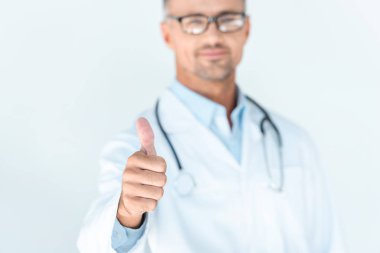 bir başparmak izole üzerinde beyaz gösterilen omuzlarında stetoskop ile gözlük yakışıklı Doktor seçici odak