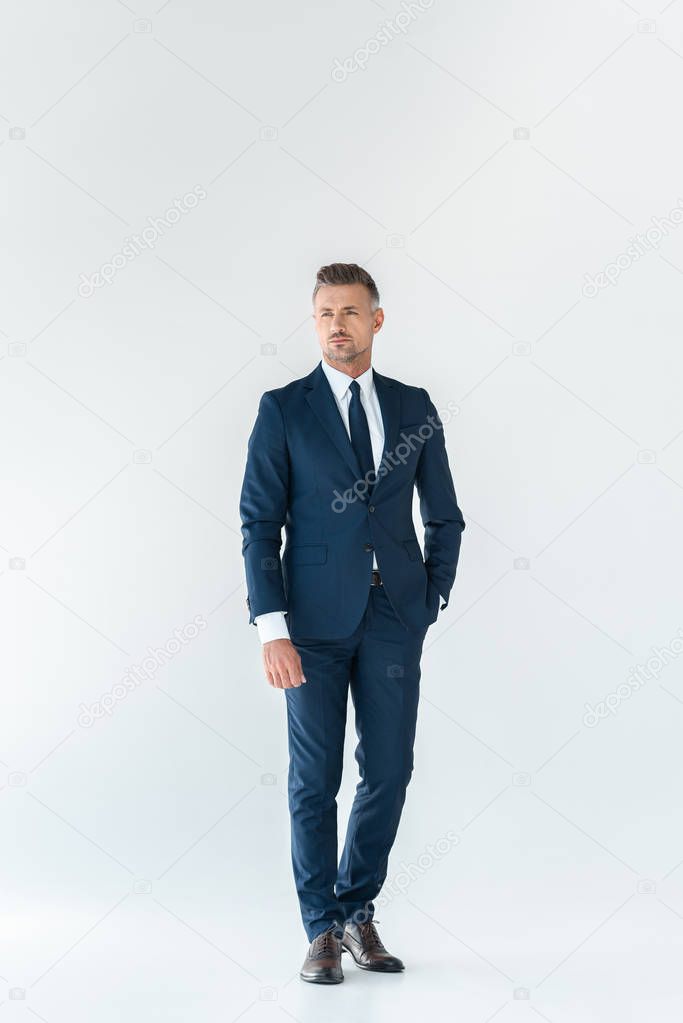 handsome businessman in blue suit standing and looking away isolated on white